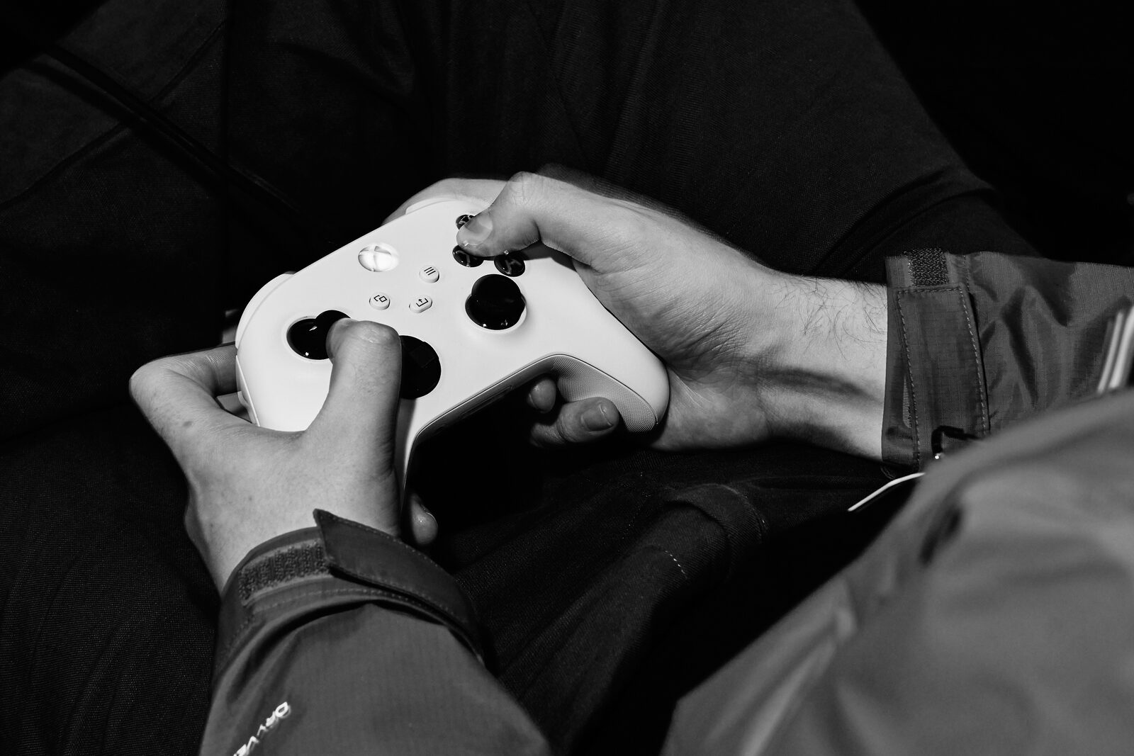 Close-up of an attendee's hands on a white Xbox controller, thumbs on the sticks.