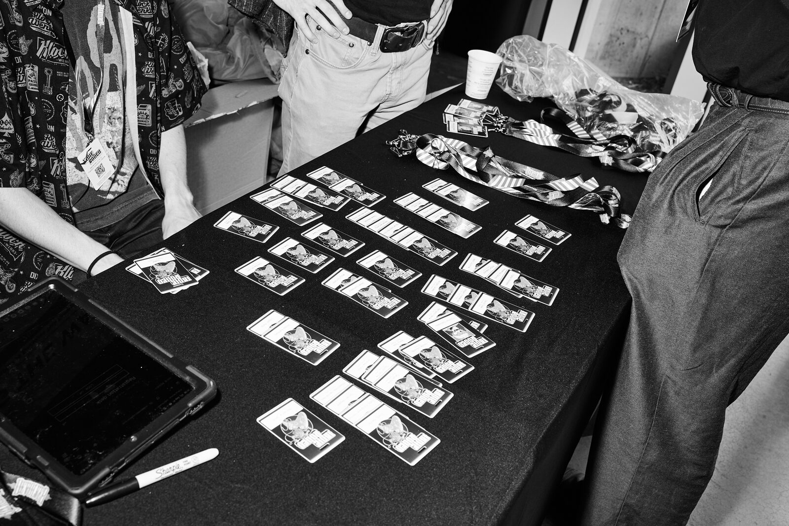 A table laid out with rows of Indie Rodeo photo cards and lanyards, attendees standing over it.