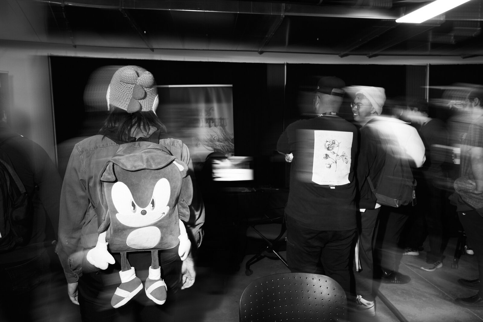 The showcase floor in motion blur — the Sonic backpack and a printed tee sharp in the middle of the drift.