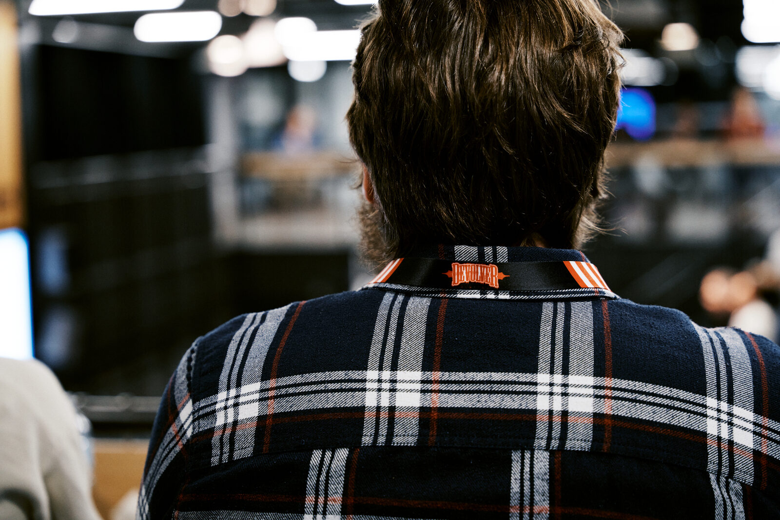 Back of an attendee's plaid shirt, the orange Indie Rodeo lanyard clipped at the collar.