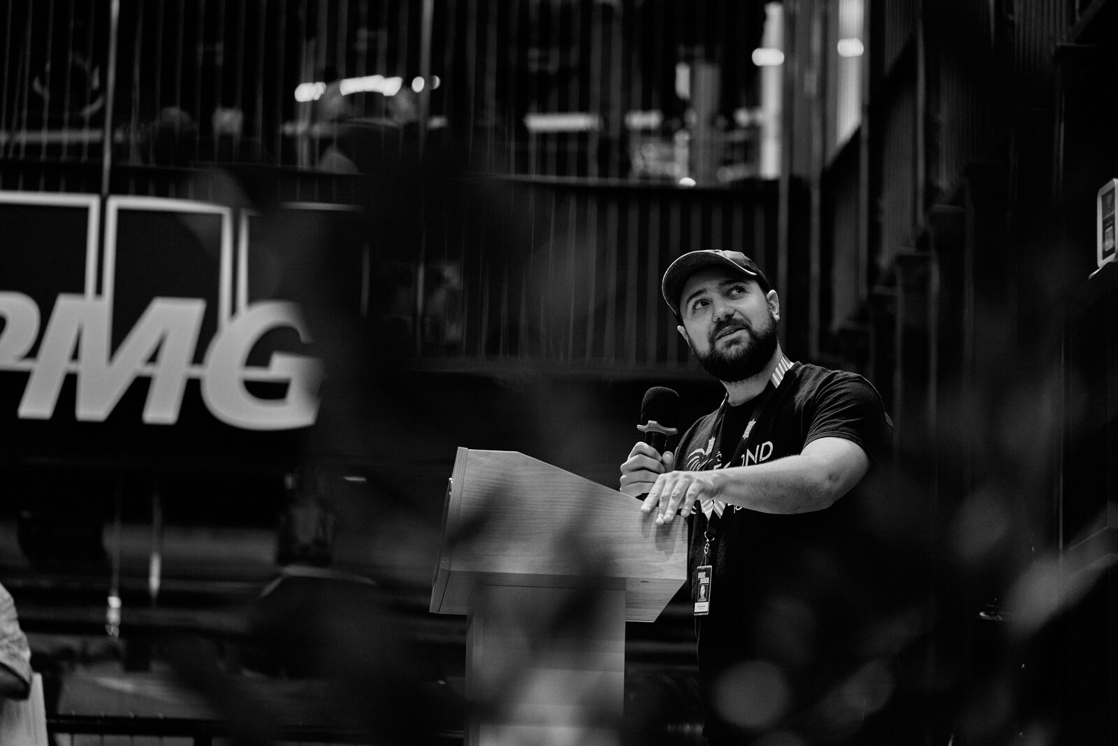 A speaker in a ball cap leans into the mic at the podium, mid-sentence, the KPMG wall behind them.