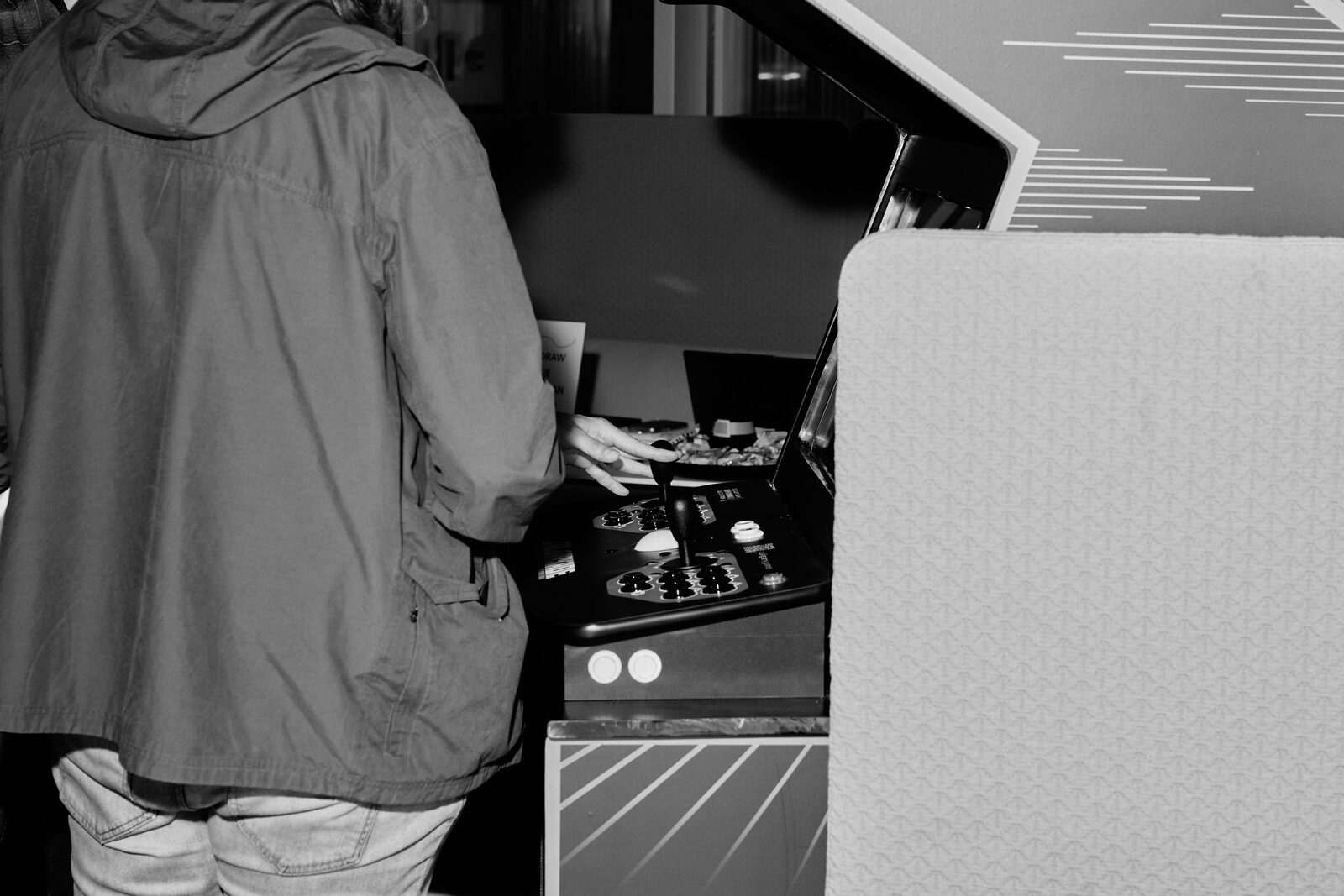 An attendee seen from behind, playing at an arcade cabinet on the showcase floor.