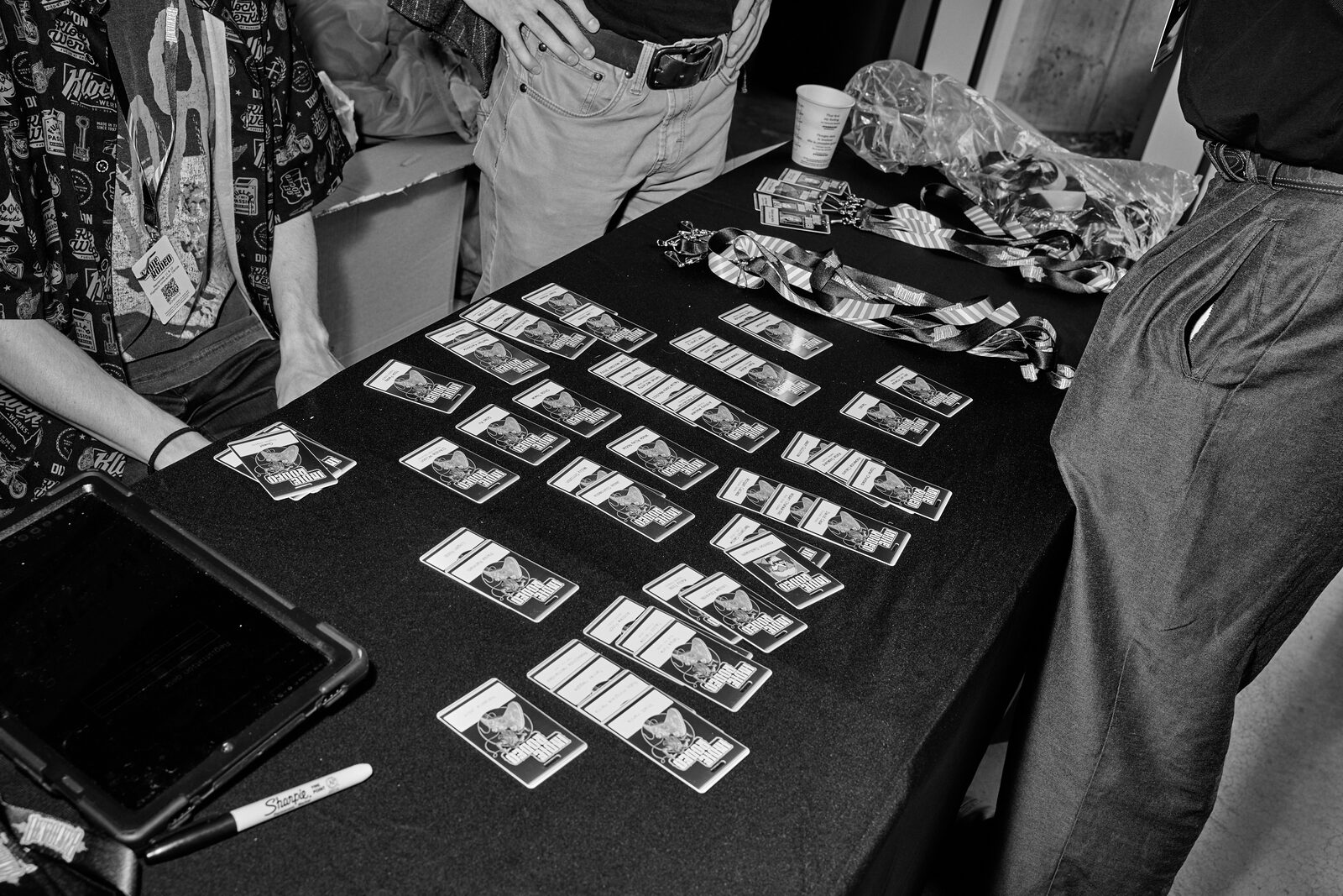 A table laid out with rows of Indie Rodeo photo cards and lanyards, attendees standing over it.