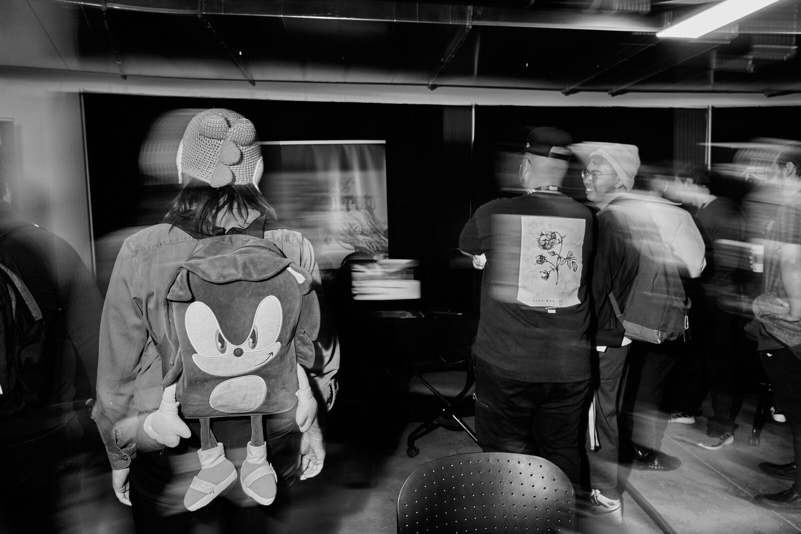 The showcase floor in motion blur — the Sonic backpack and a printed tee sharp in the middle of the drift.