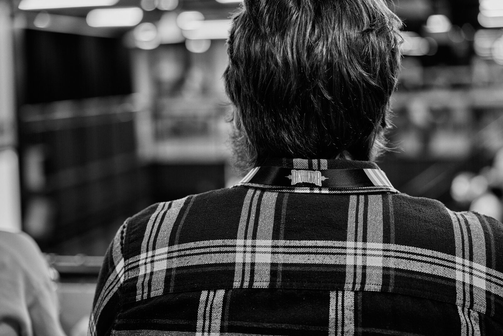 Back of an attendee's plaid shirt, the Indie Rodeo lanyard clipped at the collar.